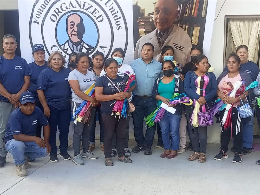 Mixteco artesanos holding bundles of woven palm at a Foundation Mixtecos Unidos gathering