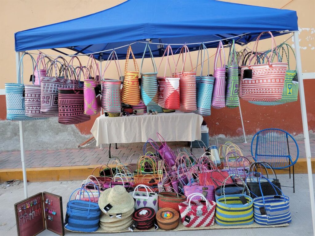 A market stall filled with brightly colored hand-woven palm baskets and bags