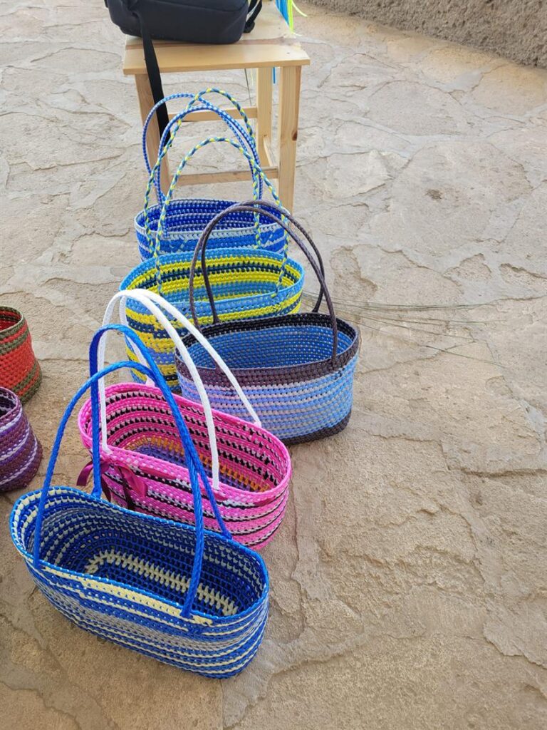 Close-up of finished hand-woven palm baskets in blues, pinks and yellows